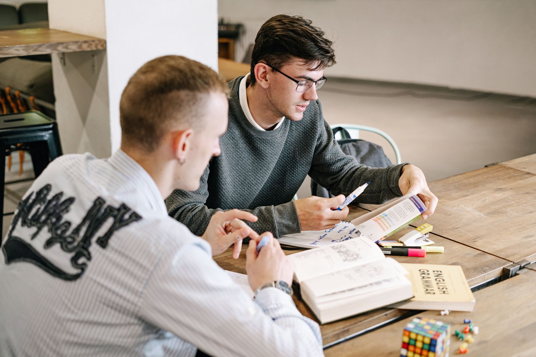 A student preparing for an English test at a desk with notes and a laptop, reflecting the IELTS, PTE and TOEFL preparation stage of the application